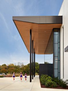 three people walking down the sidewalk under a building