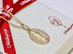 This exquisite Miraculous Medal, made in France, is a stunning piece crafted from solid sterling silver and plated with 3 microns of gold. Available for both men and women, it can be purchased with or without a chain. The medal measures 19 x 13 mm, making it a perfect size for daily wear. The Miraculous Medal is steeped in history and significance. It was originally given to St. Catherine Labouré during her visions of the Blessed Virgin Mary in 1830. The inscriptions on the medal are in French, just as they appeared in the original design. Front of the Medal: The front features an image of the Virgin Mary with the words "O Marie, conçue sans péché, priez pour nous qui avons recours à vous" ("O Mary, conceived without sin, pray for us who have recourse to thee"). This inscription highlights Miraculous Medal Pendant Gift, Yellow Gold Miraculous Medal Necklace As Gift, Yellow Gold Miraculous Medal As Gift, 14k Gold Miraculous Medal As A Gift, 14k Gold Miraculous Medal As Gift, Immaculate Conception, St Catherine, Saints Medals, Heart Of Jesus