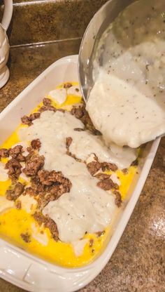 a person scooping food out of a casserole dish with cheese and ground beef