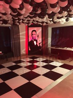 a party room with balloons and black and white checkered flooring, an image of elvis presley on the wall