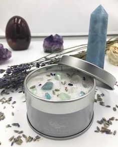 a candle sitting next to some rocks and lavenders on a table with other items in the background