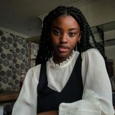 a woman with braids is looking at the camera while sitting in front of a table