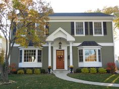 a gray house with white trim and black shutters on the front door is shown