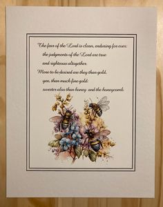 a card with two bees and flowers on it, in front of a wooden background