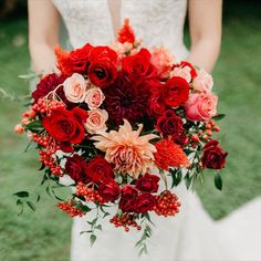 Bride holding her bouquet made with roses, dahlias, ranunculus, berries in a color palette of red, burgundy, coral, and peach. Made by Cindie Sinclair, owner and lead florist at Camrose Hill. An outdoor wedding venue and florist located in Stillwater, MN near Minneapolis. Red And Peach Bouquet, Crimson Wedding, Red Bridal Bouquet, Peach Bouquet, Red Wedding Flowers, Wedding Palette, Flower Studio, Peach Wedding, Coral Peach