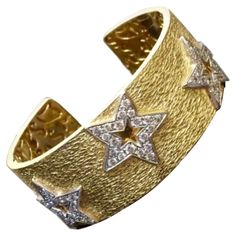 DeKara Design Collection Metal- 18K Yellow Gold, .750, 96 Grams. Stones- 100 Round Diamonds G Color VS1 Clarity 5.03 Carats. Measurements- 1 Inch Wide, 4.22 MM Thick, Stars are 21 MM x 21 MM. Entirely handmade heavy 18K Yellow Gold Diamond Star Cuff Bracelet. This bracelet has 5 white gold stars that have 20 pave diamonds on each start that have been hand assembled onto the bracelet itself. The gallery inside of the bracelet has all separately made with starts and other scroll work that gives th Luxury Cuff Bracelet With 17 Jewels For Anniversary, Luxury Cuff Bracelets For Anniversary, Yellow Gold Cuff Jewelry For Anniversary, Designer Yellow Gold Cuff Bracelet, Luxury Hallmarked Cuff Bracelet For Anniversary, Designer Cuff Bracelet For Anniversary, Designer Cuff Jewelry For Anniversary, Luxury Star-shaped Formal Jewelry, Luxury Gold Star Bracelets