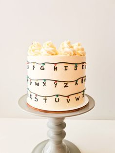 a cake with icing and letters on it sitting on top of a table in front of a white wall