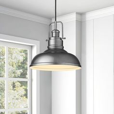 an industrial style pendant light hanging over a kitchen table with a window in the background