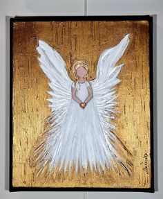 an angel painted on wood with gold and white paint is hanging from the ceiling in front of a gray wall