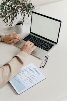 a person sitting at a desk with a laptop and papers in front of them, working on a computer