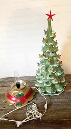 a small christmas tree sitting next to an old fashioned tea kettle on a wooden table