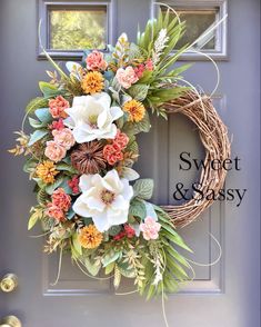 a wreath with flowers and greenery on the front door for spring or summer decorating