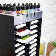 there is a black rack with many different colors of paint and inks on it