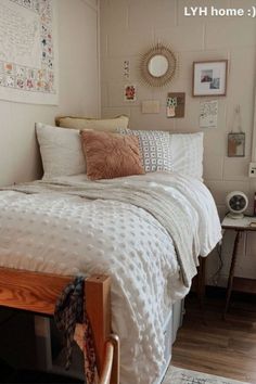 a bed with white comforter and pillows in a bedroom next to a wooden table