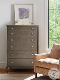 a living room with a chair, dresser and window