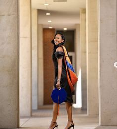 a woman is walking down the hall with her hand in her pocket and holding a blue purse