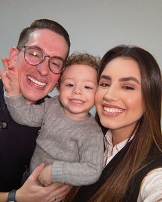 a man, woman and child are smiling for the camera with their arms around each other