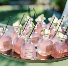 small pink bottles are lined up on a platter with sticks sticking out of them