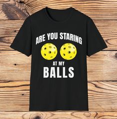 a black t - shirt that says are you staring at my balls?