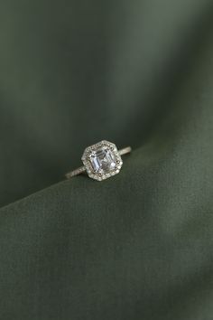 an engagement ring on top of a green cloth