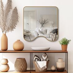 a mirror on the wall above a shelf with vases and other items in front of it