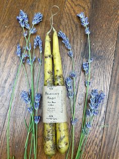 some purple flowers are on a wooden table and there is a roll of soap in the middle