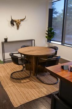 an office with a cow head mounted on the wall and wooden table surrounded by black chairs