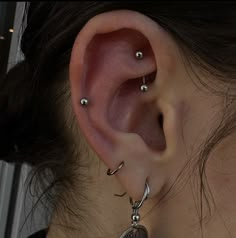 a close up of a person's ear with some piercings on it,