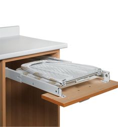 an open drawer on the side of a wooden desk with a white tray underneath it