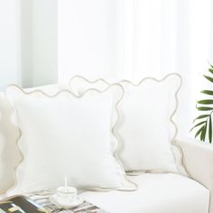 a white couch sitting next to a window in a living room with pillows on top of it