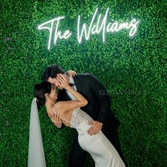 a bride and groom kissing in front of a green wall with the words'the williams '