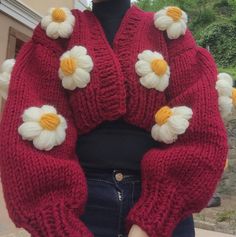 a woman is wearing a red sweater with white flowers on the shoulders and arms,