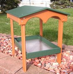 a small wooden table sitting on top of a pile of rocks next to a grass field