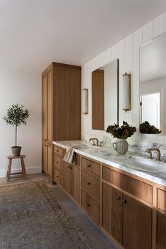 a large bathroom with two sinks and wooden cabinets in the corner, along with a rug on the floor