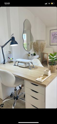 a desk with a mirror, chair and lamp in a room that has white walls