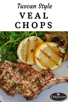 a white plate topped with meat next to lemon wedges and green salad leafy greens