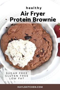 a white bowl filled with brownie and whipped cream next to strawberries on a plate