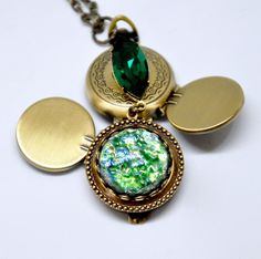 "Here is a lovely handmade necklace featuring a unique 4 picture locket. The locket has been decorated with a shimmering Harlequin art glass green fire opal and is accented with a beautiful Swarovski emerald navette crystal. This locket has the shape of a pocket watch, but springs open via the top latch to reveal four slots for photos. Perfect for showcasing multiple pictures of loved ones and family. Locket measures 1\" wide. Full pendant measures 2 5/8\" long. Antique brass finished textured c Mood Jewelry, Necklace Emerald, Picture Locket, Dragons Breath, Multiple Pictures, Green Fire, Photo Locket Necklace, Filigree Earrings, Bird Earrings