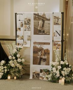 flowers and candles sit on the floor next to a wall with posters, photos, and pictures