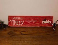 a wooden sign that says christmas trees with a truck and pine cones in the background