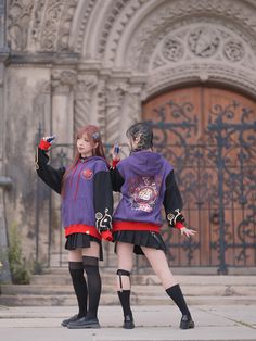 two young women dressed in costumes standing on the side of a building with their arms outstretched