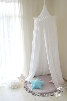 a white canopy bed with blue stars on the floor in front of a curtained window