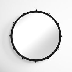 a round mirror hanging on the wall with black studded frame and metal rivets