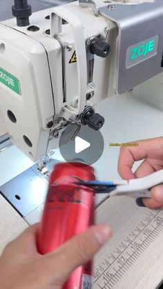 someone is using a sewing machine to sew on something red and white in front of them