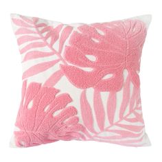 a pink and white pillow with palm leaves on the front, in an embroidered pattern