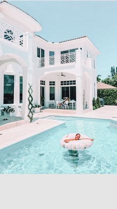 an inflatable floater floating on top of a pool next to a large white house