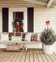 a white bench sitting on top of a wooden floor next to a christmas wreath and potted plant