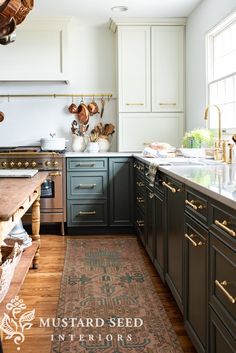 a kitchen with wooden floors and green cabinets, an area rug in front of the sink