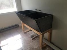 a black sink sitting on top of a wooden stand next to a window in a bathroom