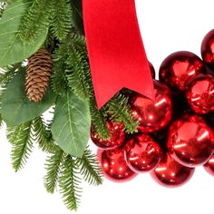 a bunch of christmas balls with a red ribbon on it and some pine cones in the background